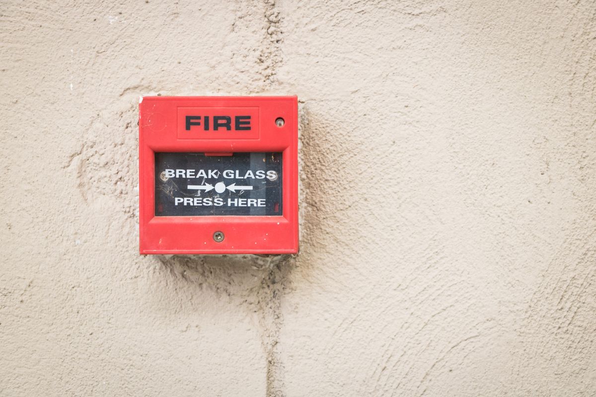Red break-glass fire alarm pull station mounted on a building wall