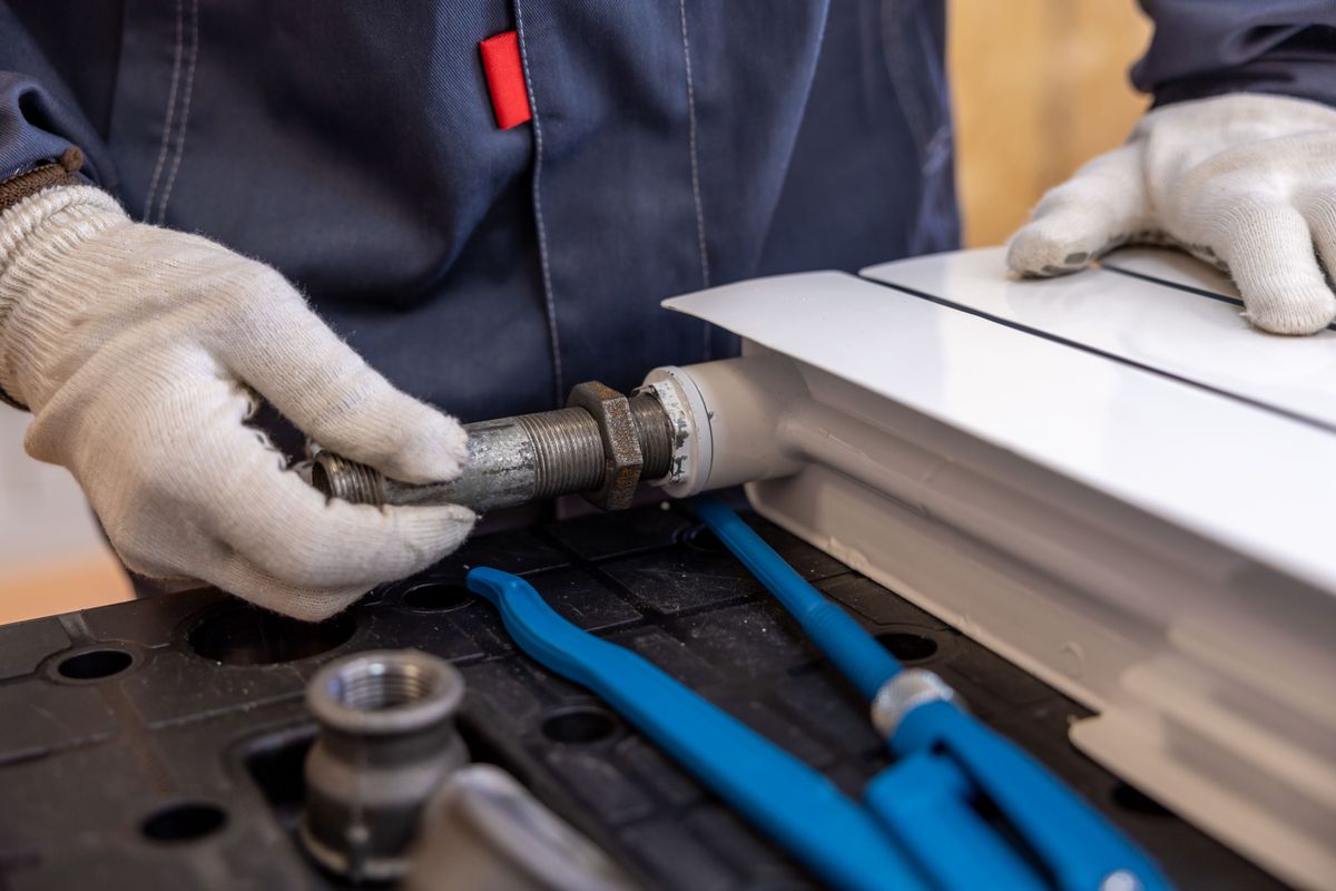 Plumber fitting a water supply line with pipe wrenches
