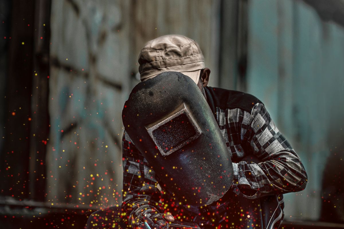 Welder in a helmet grinding and welding steel with sparks flying